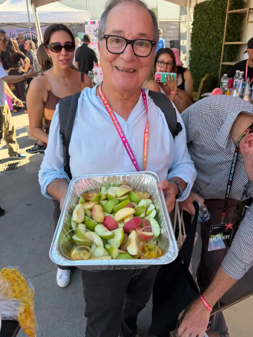 A guest holding a foil tray of apple slices in the crowd