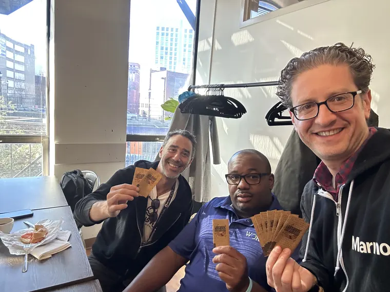 Jordan Isenstadt with guests at a cafe table holding up cards