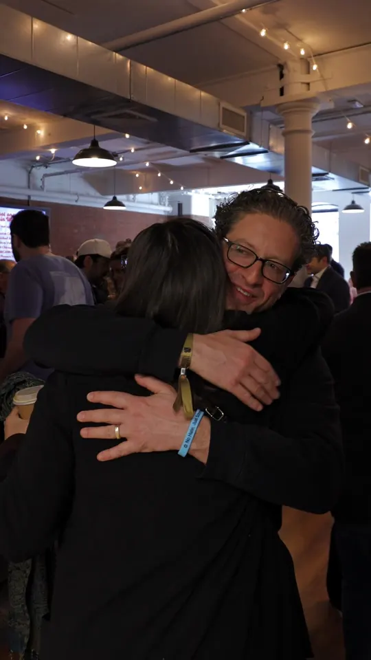 Two attendees hugging at the door