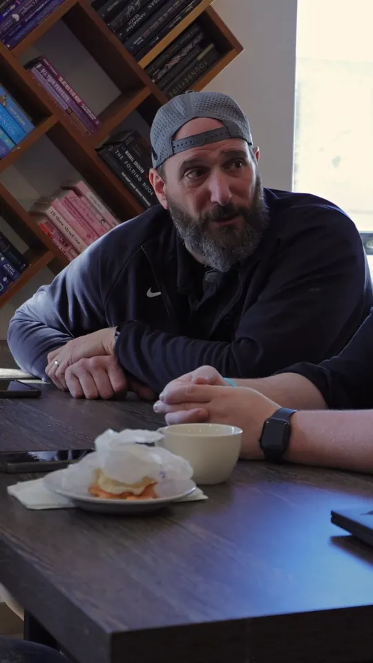 Attendee at a cafe table with coffee and a bagel