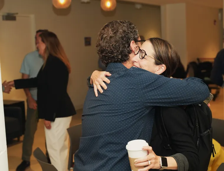 Two attendees hugging hello