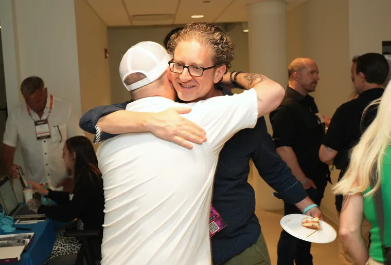 Two attendees embracing in the middle of the crowd