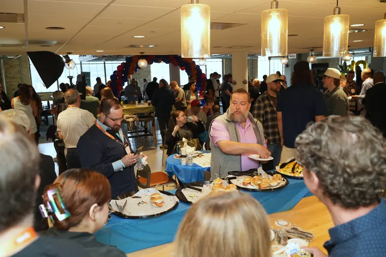 Crowd around the bagel buffet under pendant lights