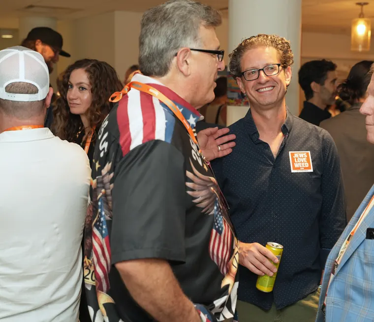 Two attendees laughing, one in a flag-print shirt