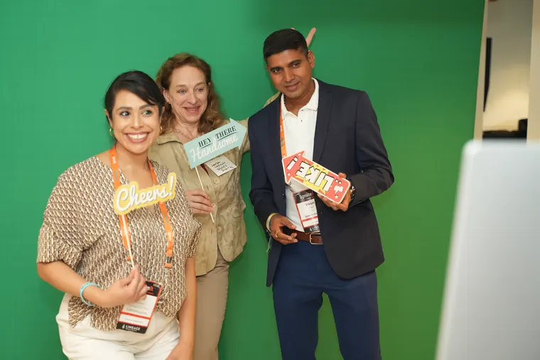 Three guests posing with props at the green screen