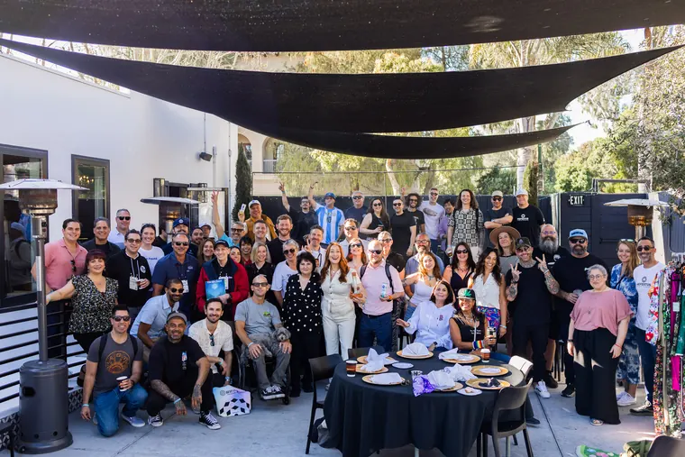 Full group photo of the Hall of Flowers Bagel Bash crowd under black shade sails at White House Beach Club