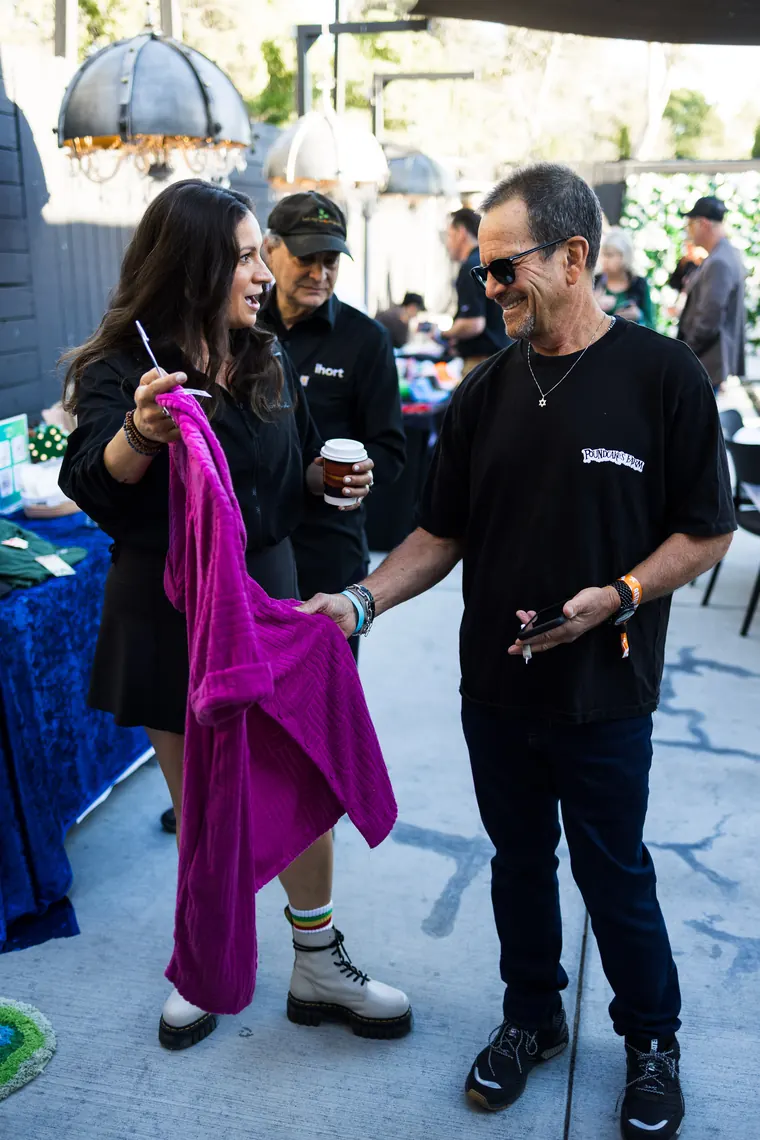 Two attendees laughing beside a rack of colorful clothing