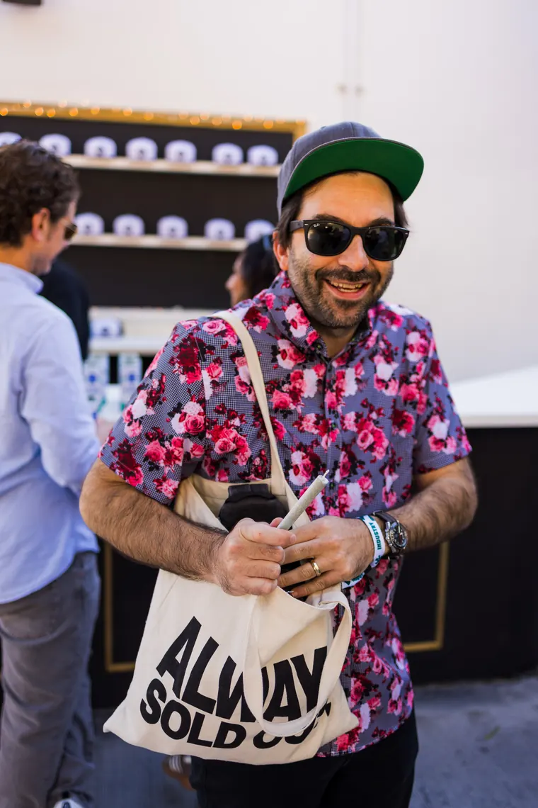 Guest in a floral shirt carrying a canvas tote, grinning