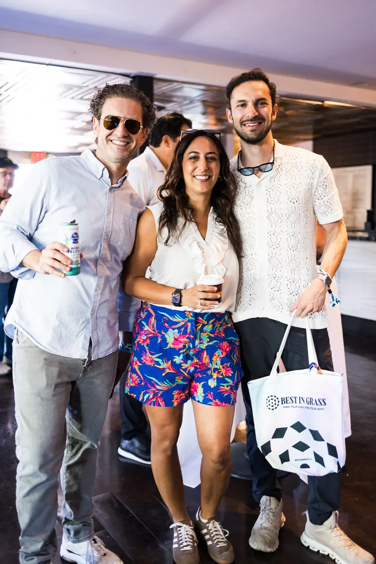 Three guests posing with a sponsor tote bag