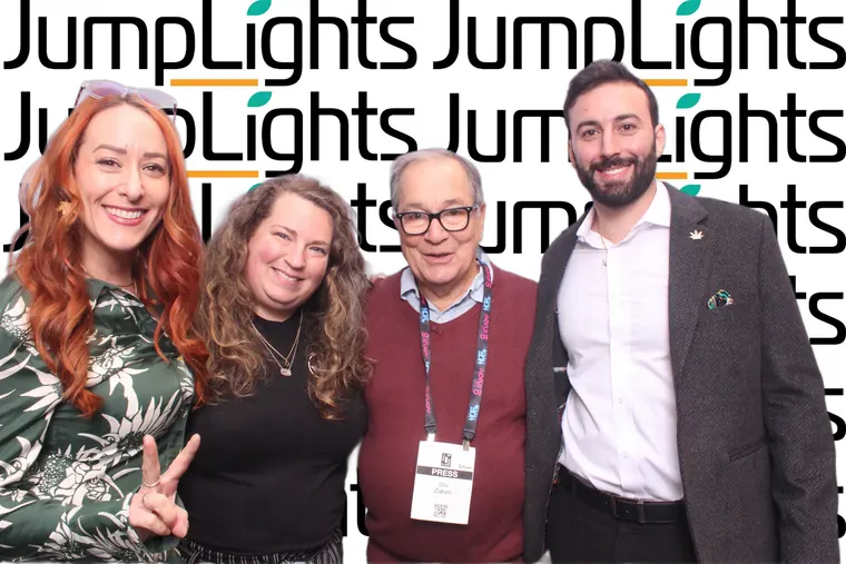 Four guests posing in front of the JumpLights photo booth backdrop