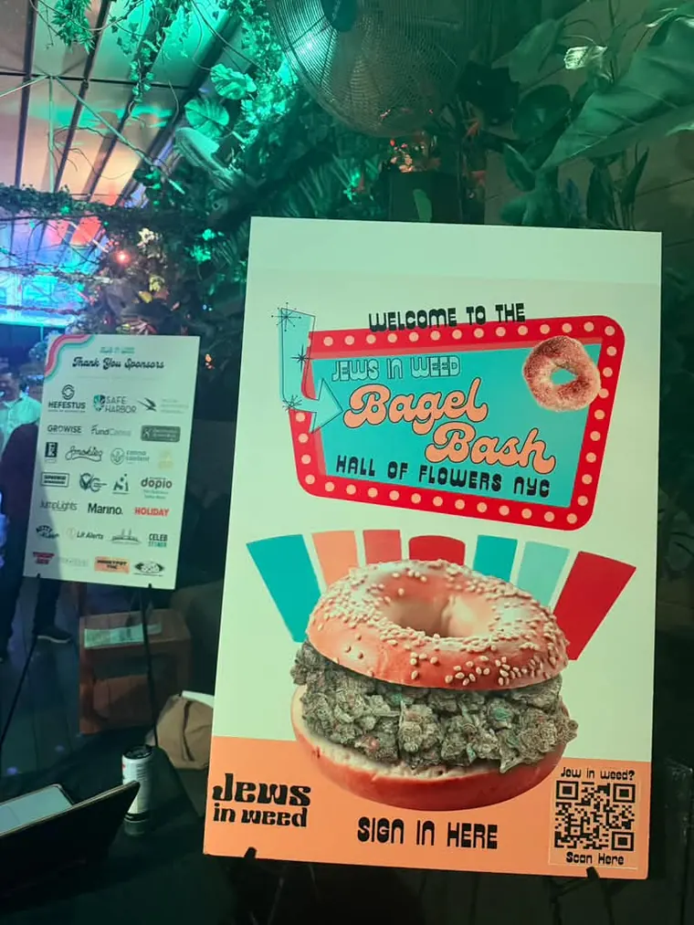 Bagel Bash Hall of Flowers NYC welcome sign with a sign-in QR code, beside the sponsor board