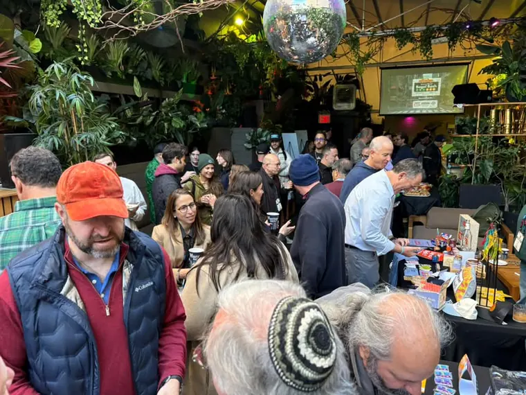 Guests browsing a vendor table, one in an orange cap