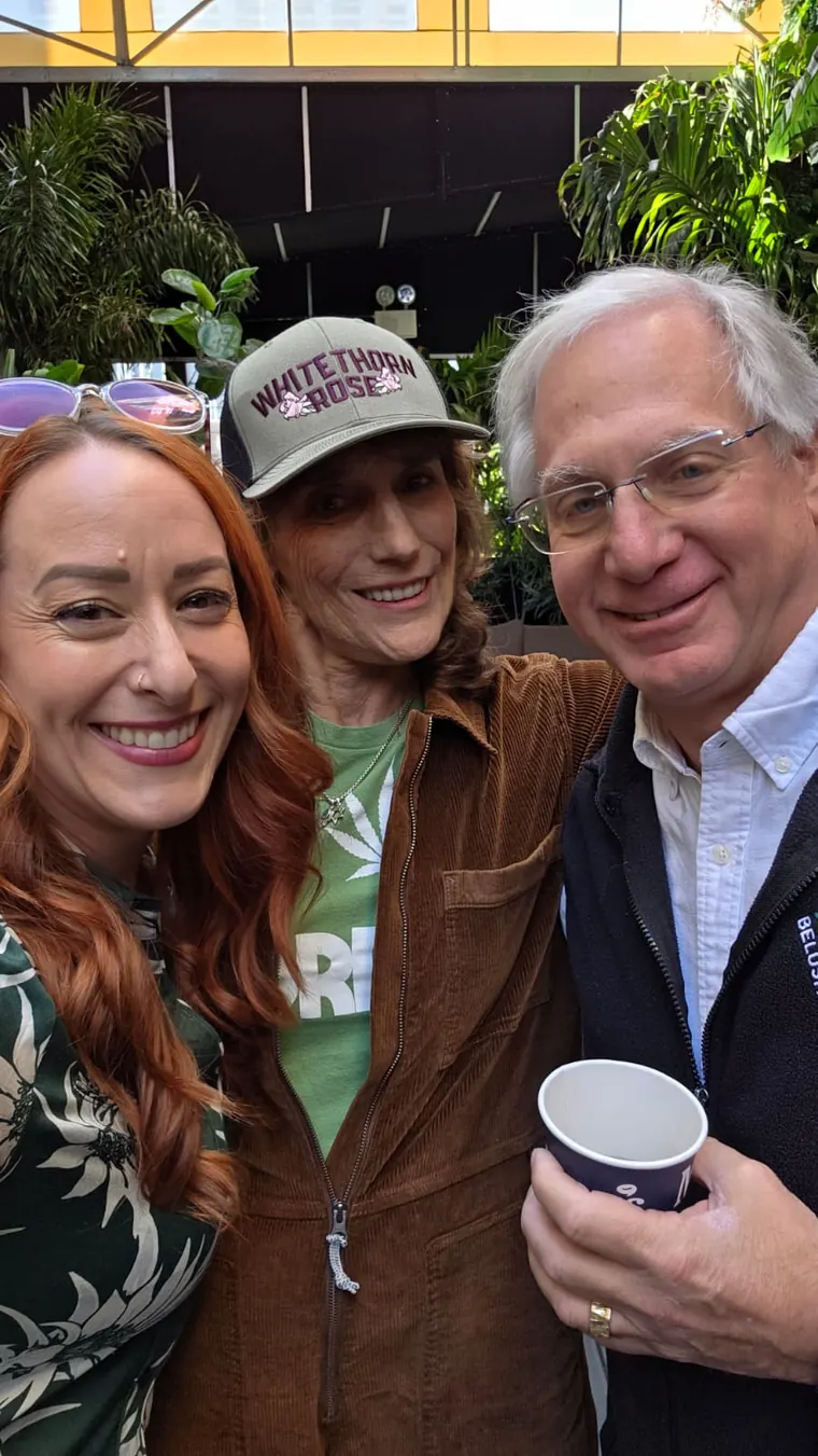 Three guests posing together, one holding a coffee