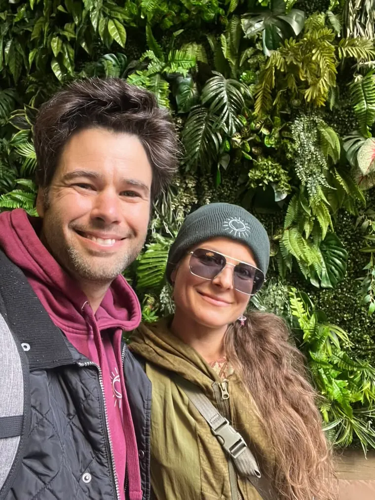 Two friends taking a selfie in front of the plant wall
