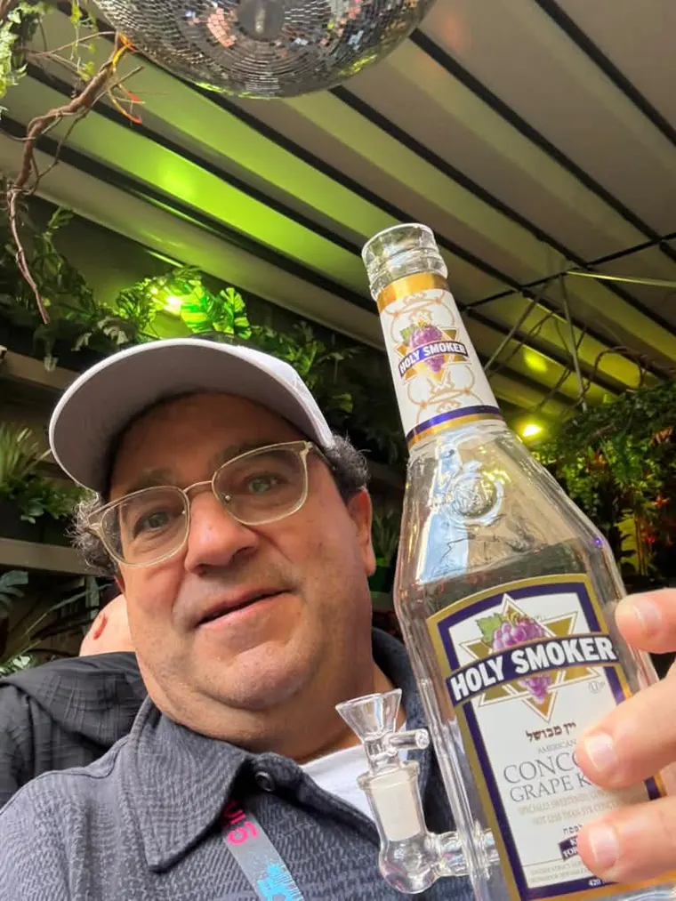 Guest raising a bottle of Holy Smoker Concord grape