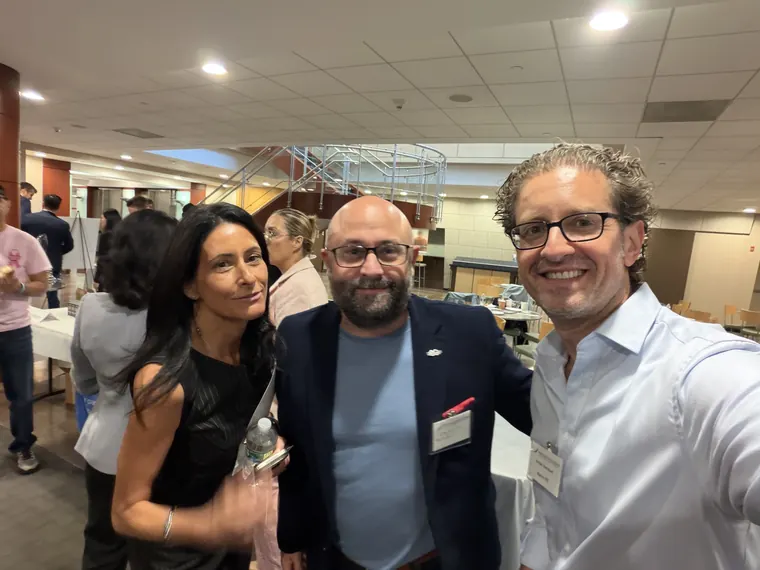 Jordan Isenstadt with three attendees in front of the exhibitor tables