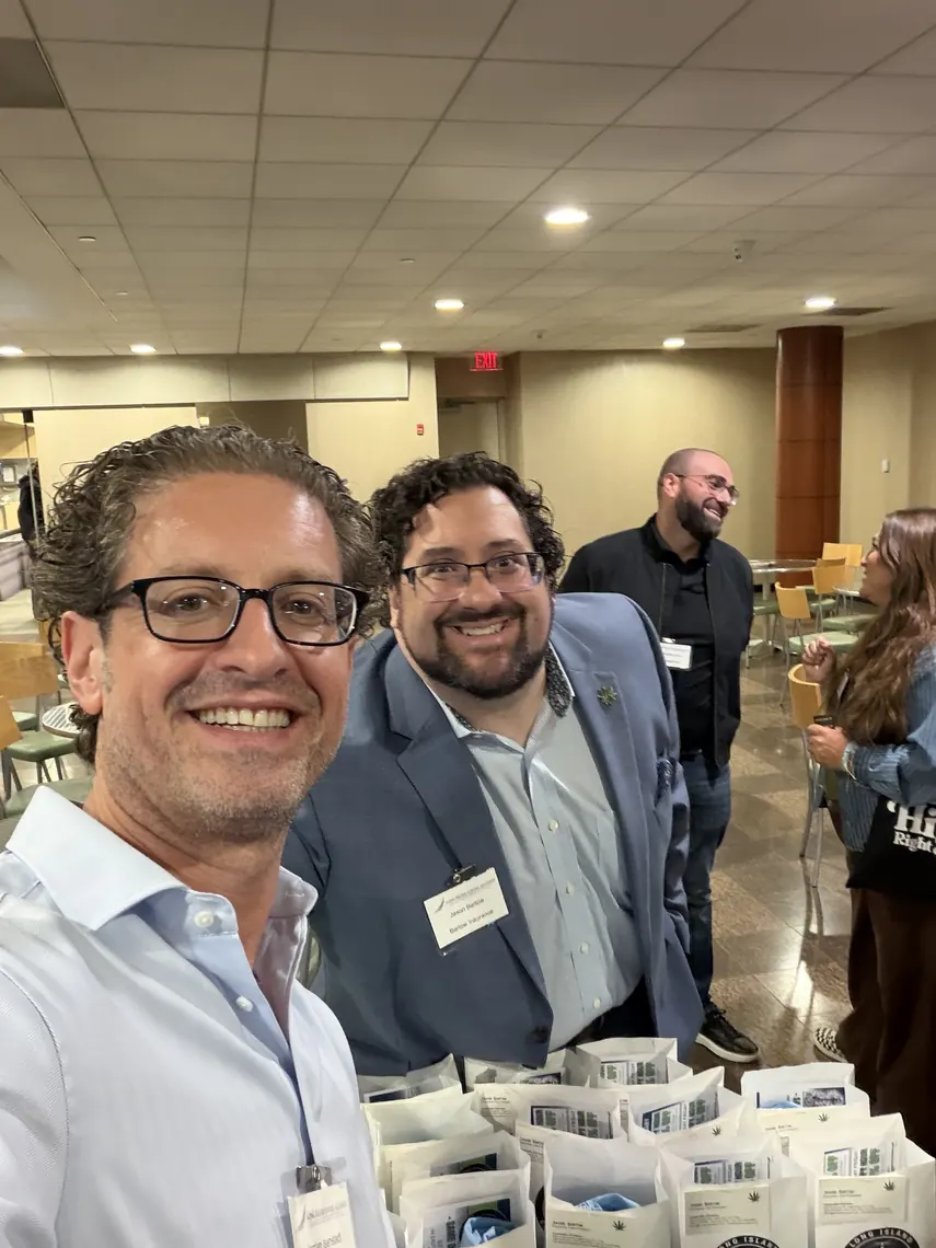 Jordan Isenstadt with an attendee beside a table lined with swag bags