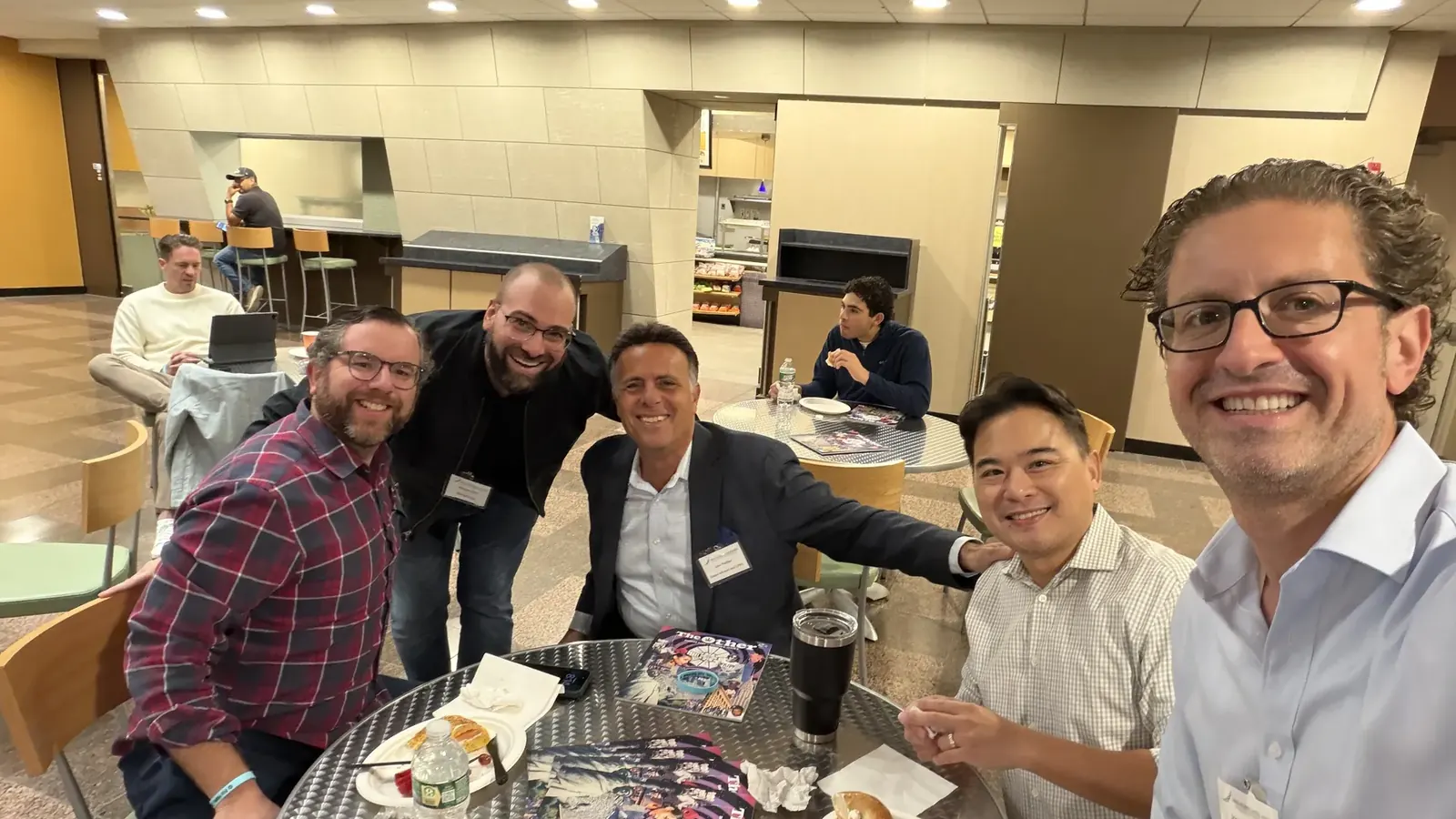 Guests gathered around a table with coffee and bagels at the Long Island Bagel Bash