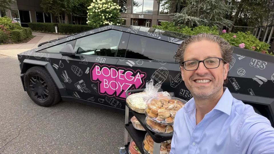 Jordan Isenstadt takes a selfie in front of a Bodega Boyz Cybertruck with bagel trays at the Long Island Bagel Bash