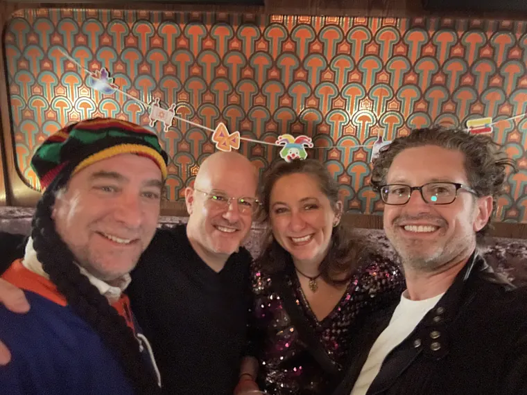 Four guests in a booth under Purim decorations, one in a striped knit hat
