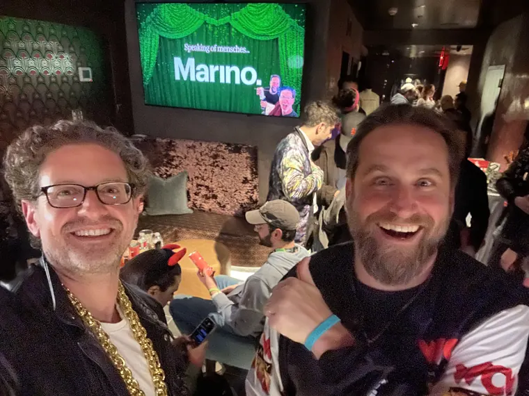 Jordan Isenstadt with a guest under a screen showing a Marino sponsor slide